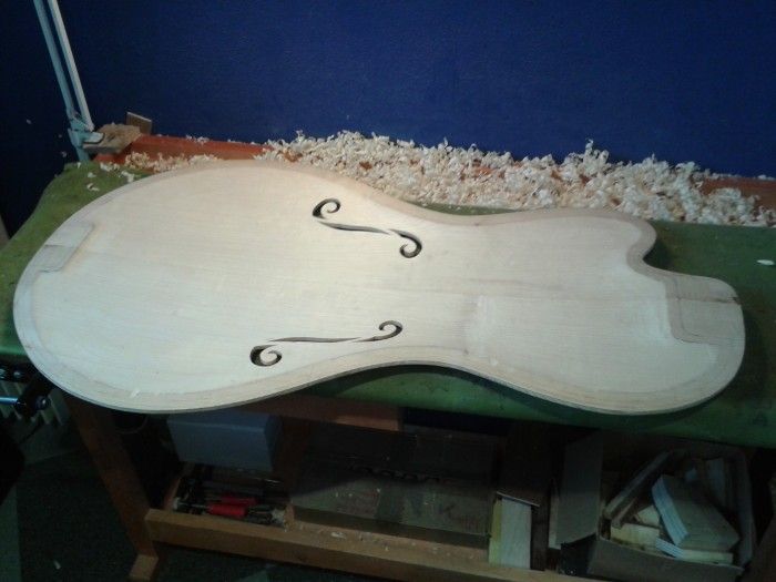 Table de guitare jazz avec ses ouïes, posée sur l'établi parmi les copeaux