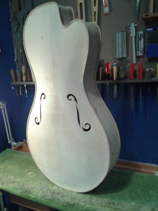 Caisse de guitare jazz en blanc, avant vernis, devant le mur d'outils