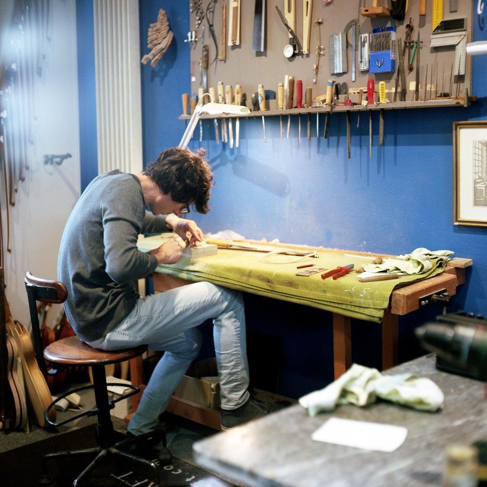 Hugo Abecassis au travail à l'établi, devant le mur d'outils